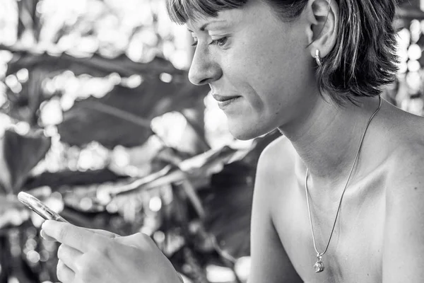 Frau mit Smartphone im tropischen Garten. Urlaub. tropische insel nusa limbongan, bali, indonesien. — Stockfoto