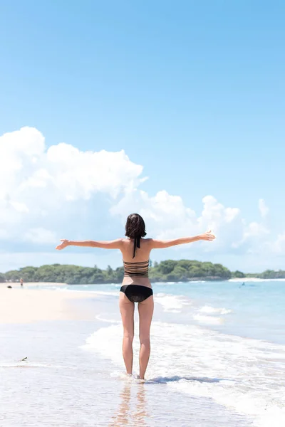 Strandvakantie. Gelukkige vrouw genieten van zonnige dag op het strand. Open armen, vrijheid, geluk en zaligheid. Tropische concept, Bali eiland. — Stockfoto