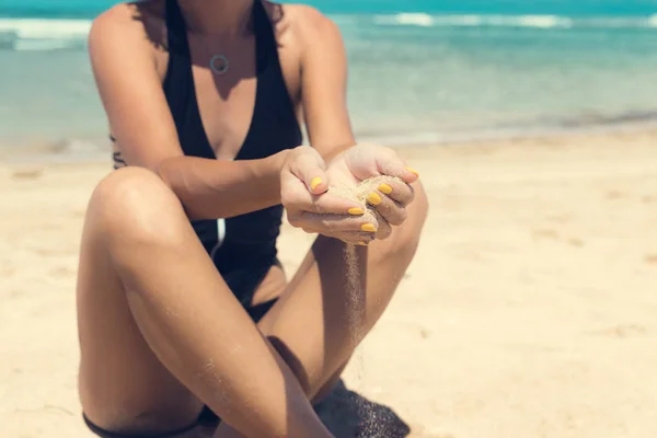Arena como el tiempo se desliza a través de sus dedos. Chica sosteniendo un fondo marino de arena. Concepto de vacaciones en climas más cálidos, el viaje al mar. Isla de Bali, Indonesia . — Foto de Stock