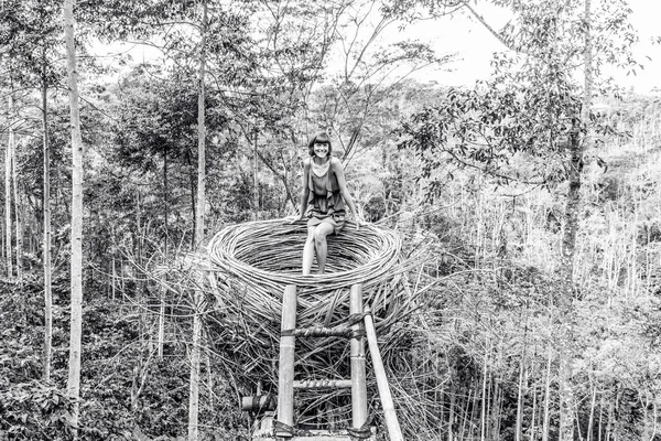 Young woman in artificial nest in rainforest of tropical Bali island, Indonesia.