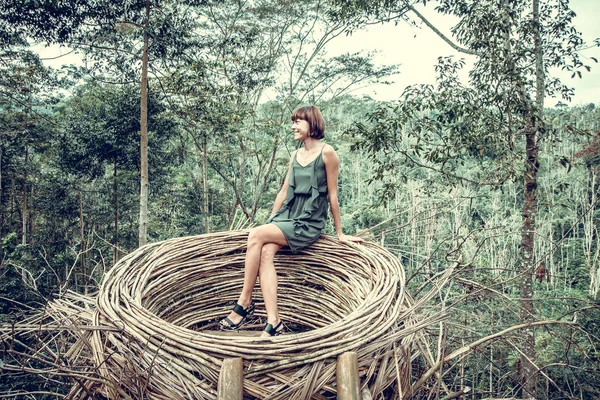 Young woman in artificial nest in rainforest of tropical Bali island, Indonesia.