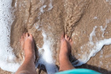 Bacaklar kişinin bir kum üzerinde. Bir adam üzerinde kum iyon sahile yukarıdan ayakta bacaklar. Yatay açık havada vurdu. Bali Adası.
