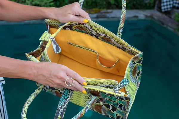 Modische Frau mit Luxus-Pythontasche aus Schlangenhaut. Elegantes Outfit. Nahaufnahme der Handtasche in den Händen der stilvollen Dame. Model posiert in der Nähe des Schwimmbades. bali-Insel. — Stockfoto