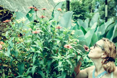 Açık havada tropikal egzotik Bali Adası, Endonezya'nın parkta çiçekleri koklamak kadın.