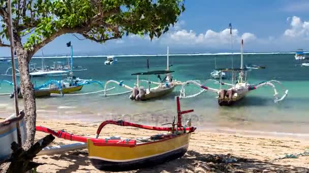 4K lapso de tiempo del barco de madera tradicional balinés con decoración de cinta en la orilla del océano bajo el cielo azul y el árbol verde. Bali tropical beach landscape, Indonesia . — Vídeo de stock