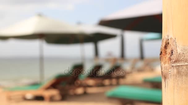 Parasols en chaise longues op een tropisch strand voor het exotische Bali, Indonesië. Onscherpe achtergrond. — Stockvideo