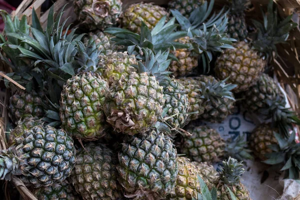 Pile of tropical organic pineapples fruits in basket for sell in tradtional farmer market of Bali island, Indonesia. — Stock Photo, Image