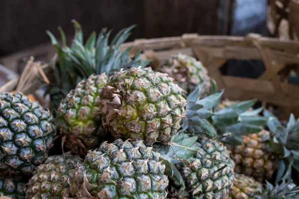 Pile of tropical organic pineapples fruits in basket for sell in tradtional farmer market of Bali island, Indonesia. — Stock Photo, Image