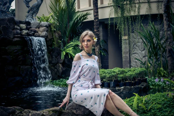 Vrouw is poseren in een tropische tuin van Bali eiland, Indonesië. Tuin waterval op een achtergrond. Sexy jonge vrouw. — Stockfoto