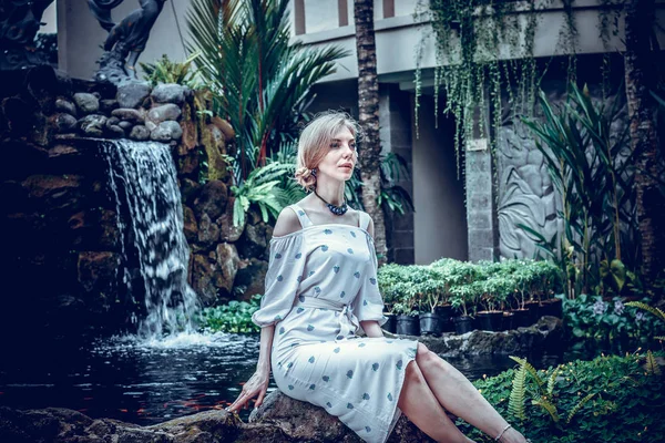 Vrouw is poseren in een tropische tuin van Bali eiland, Indonesië. Tuin waterval op een achtergrond. Sexy jonge vrouw. — Stockfoto