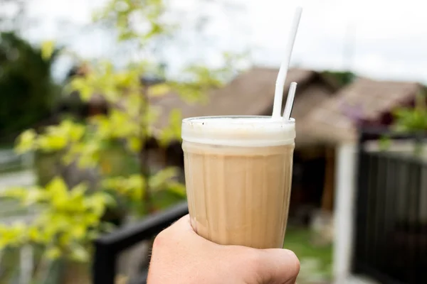 Gelo café latte em vidro mão homem em um belo fundo natureza. Ilha Tropical de Bali, Indonésia . — Fotografia de Stock