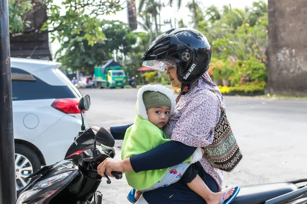 BALI, INDONESIA - JUNE 2, 2017: Potret ibu Bali dengan anak-anaknya di tangan duduk di atas sepeda motor. Indonesia . — Stok Foto