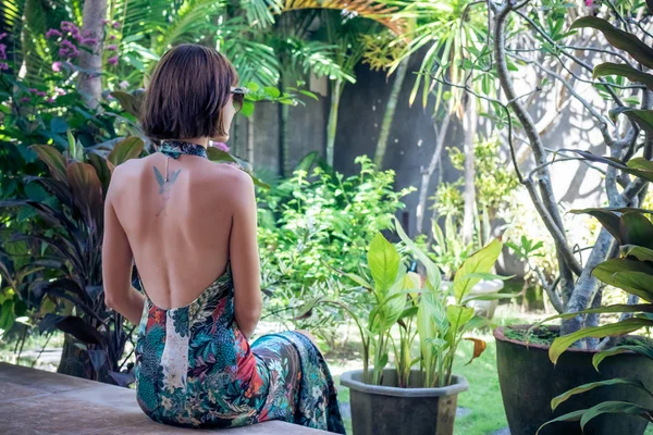 Aantrekkelijke jonge vrouw in een mooie zijden jurk onder de tropische planten. Vakantie. Tropen. Fashion schot. Bali eiland. — Stockfoto