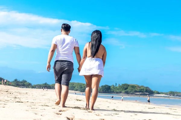 Asian couple walking on the beach of tropical Bali island, Indonesia.