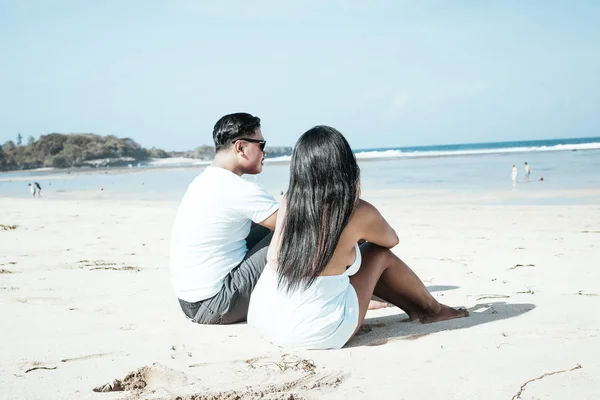 Casal asiático sentado na praia da ilha tropical de Bali, Indonésia . — Fotografia de Stock