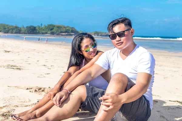 Pareja asiática sentada en la playa de la isla tropical de Bali, Indonesia . — Foto de Stock