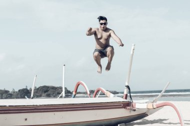 Genç Asyalı Endonezya adam tropikal Bali Adası, Endonezya kumsalda eğleniyor.