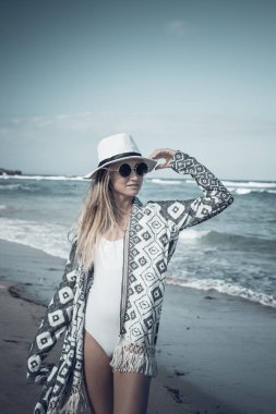 Beyaz şapka üzerinde beyaz kum plaj tropikal bir Bali Adası güneşli gün yürüyüş ile genç seksi kadın. Okyanus maliyet.