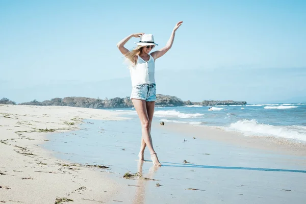 Молодая сексуальная женщина в белой шляпе, гуляющая по белоснежному песчаному пляжу тропический остров Бали в солнечный день. Стоимость океана . — стоковое фото