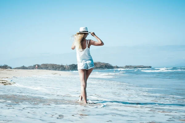 Jonge sexy vrouw met witte hoed wandelen op witte zand strand een tropisch eiland Bali's zonnige dag. Kosten van de Oceaan. — Stockfoto