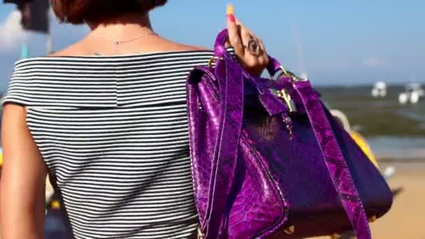 Mujer caminando en la playa con una bolsa de piel de serpiente de pitón de lujo. Isla tropical Bali, Indonesia . — Vídeo de stock