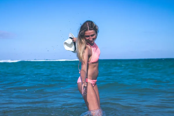 Beautiful young woman in bikini on the beach splashing water. Tropical island Bali, Indonesia. — Stock Photo, Image