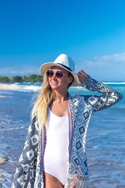 Portrait d'une jeune femme sexy avec chapeau blanc et lunettes de soleil marchant sur la plage de sable blanc une île tropicale de Bali par une journée ensoleillée. Coût des océans . — Photo