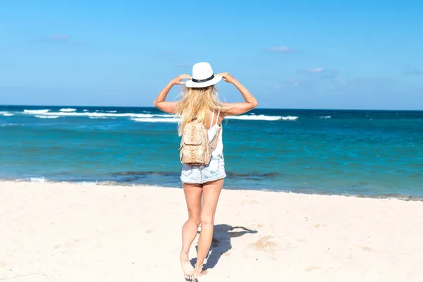 Jonge sexy vrouw met witte hoed en luxe slangenhuid python rugzak wandelen op witte zand strand een tropisch eiland Bali's zonnige dag. Kosten van de Oceaan. — Stockfoto
