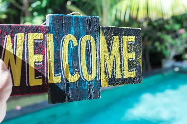 Wooden board with text welcome in man hand. Bali island. Welcome sign. — Stock Photo, Image