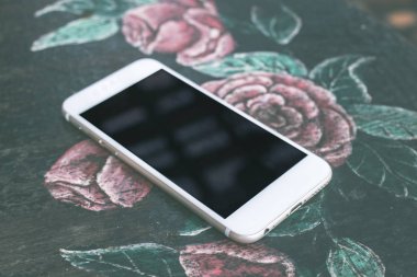 Beyaz cep telefonu kafede vintage masa örtüsü üzerine boş siyah perde ile mockup görüntüsü. Bali Adası.