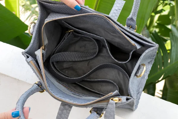 Woman holding luxury snakeskin python handbag. Bali island. Fashion bag concept on a tropical island.