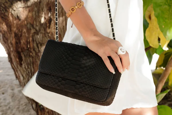 Modelo morena moda em vestido branco posando na praia. Usando óculos de sol e bolsa de luxo handmande snakeskin python. Bali, Indonésia . — Fotografia de Stock