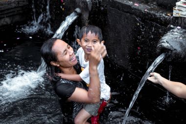 Bali, Endonezya - 5 Mayıs 2017: Kutsal bahar su Tirta Empul Hindu tapınağı, Bali Endonezya. Kadın oğluyla.