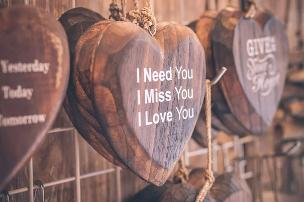 Trä hjärtan placeras fint på en turkos vintage trä bakgrund. Handgjorda trä hjärtan med text i souvenirbutiken på ön Bali, Indonesien. Pastell filter. — Stockfoto