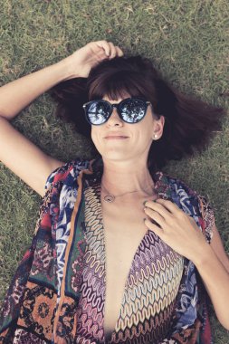 Otların arasında rahatlatıcı. Güzel genç kadın güneş gözlüğü ve tropikal Bali Adası, Endonezya'nın parkta yeşil çim üzerinde yalan pareo Üstten Görünüm.