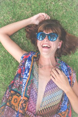 Otların arasında rahatlatıcı. Güzel genç kadın güneş gözlüğü ve tropikal Bali Adası, Endonezya'nın parkta yeşil çim üzerinde yalan pareo Üstten Görünüm.