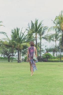 Çıplak ayakla tropikal yeşil alan üzerinde yürüyen kadın. Bali Adası, Endonezya. Nusa Dua park.
