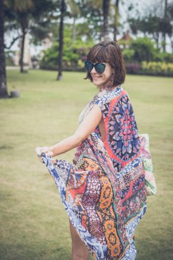 Çıplak ayakla tropikal yeşil alan üzerinde yürüyen kadın. Bali Adası, Endonezya. Nusa Dua park.