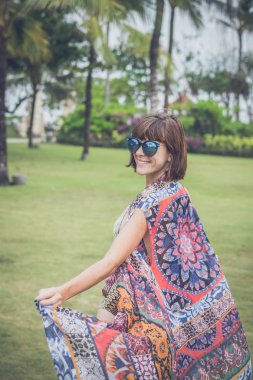 Çıplak ayakla tropikal yeşil alan üzerinde yürüyen kadın. Bali Adası, Endonezya. Nusa Dua park.