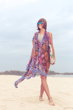 Güneş gözlüğü ve plaj çantası seyahat tatil günlerinde rahatlatıcı bir tropikal yaz tatil plaj üzerinde yürüyen kadın turist. Genç Bayan lüks moda beachwear, Bali Adası, Endonezya.