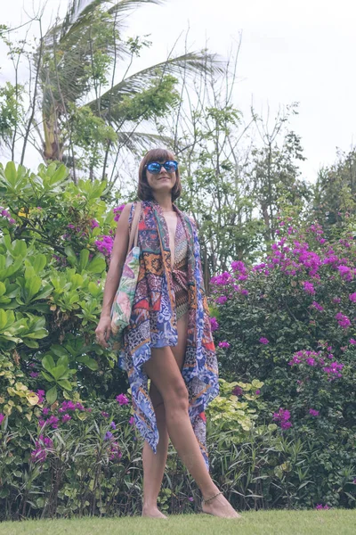 Belle fille en maillot de bain et paréo posant sur fond de fleur dans la nature de l'île de Bali, Indonésie . — Photo
