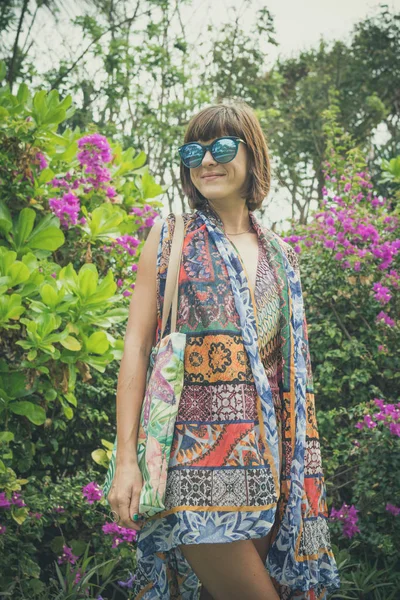 Güzel kız bir mayo ve çiçek arka planda Bali Adası, Endonezya'nın doğa poz pareo.