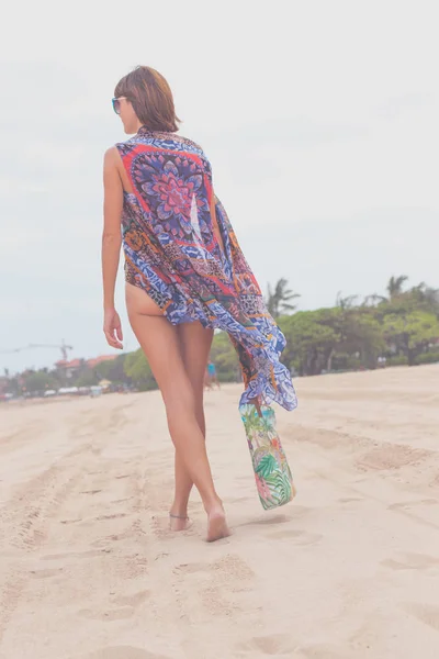 Touristin, die mit Sonnenbrille und Strandtasche an einem tropischen Sommerurlaubsstrand spazieren geht und sich im Urlaub entspannt. junge Dame in luxuriöser Mode Beachwear, Bali Island, Indonesien. — Stockfoto