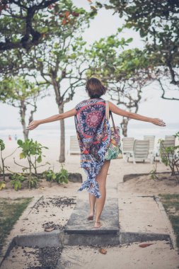 Özgürlük kavramı. Pareo ve mayo plaj çantası plaj girme ile bir genç kadın. Tropik ada Bali, Endonezya.