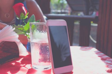 Mockup beyaz cep telefonu ile restoran ve bir bardak su kırmızı arka plan boş beyaz ekran görüntüsü. Tropikal Bali Adası, Endonezya.