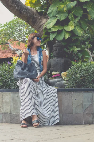 Vrouw in zonnebril met mode slangenhuid python tas zitten buiten. Bali eiland, Indonesië. — Stockfoto