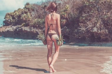 Egzotik ananas meyve, Cennet Adası Bali ile sahilde yürüyen seksi tropikal kadın. Sağlıklı beslenme kavramı. Endonezya.