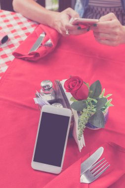 Boş beyaz ekran restoranda kırmızı zemin üzerine beyaz cep telefonuyla mockup görüntüsü. Tropikal Bali Adası, Endonezya. Arka plan bulanık smartphone ile kadın el.