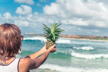 Kadın el okyanus zemin üzerine taze ananas egzotik meyve ile. Taze sağlıklı diyet gıda kavramı. Bali Adası.