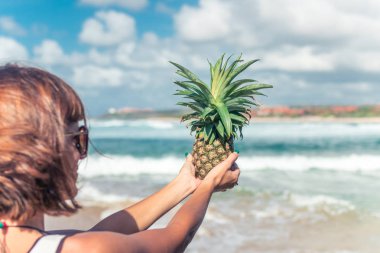 Kadın el okyanus zemin üzerine taze ananas egzotik meyve ile. Taze sağlıklı diyet gıda kavramı. Bali Adası.